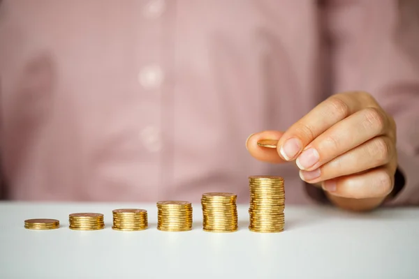 Weibliche Hand stapelt Goldmünzen in zunehmenden Säulen — Stockfoto