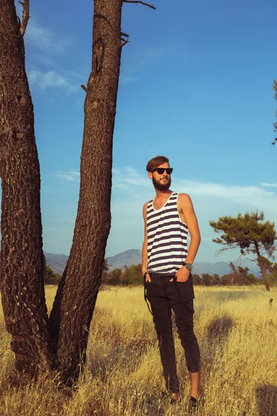 Jonge stijlvolle knappe man in de savanne — Stockfoto