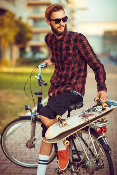 Stylish man in sunglasses riding a bike on city street — Stock Photo, Image