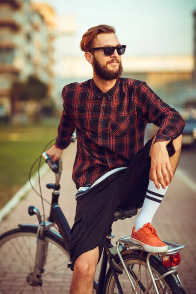 Uomo elegante in occhiali da sole in bicicletta sulla strada della città — Foto Stock