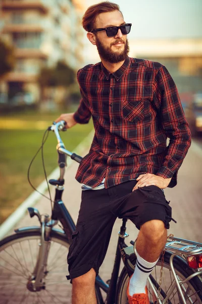 Uomo elegante in occhiali da sole in bicicletta sulla strada della città — Foto Stock