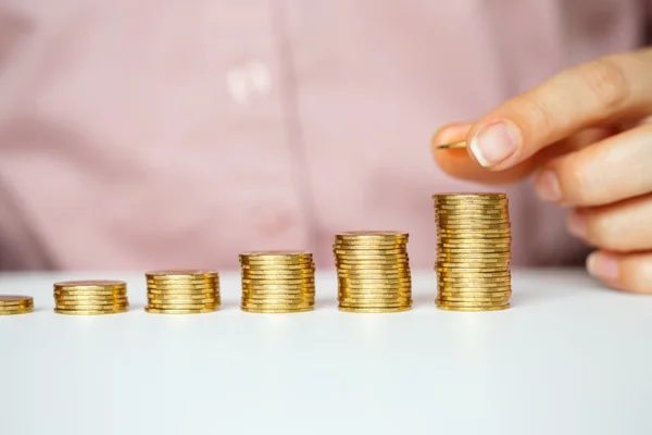 Mano femenina apilando monedas de oro en columnas crecientes — Foto de Stock