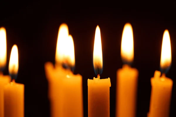 Багато палаючих свічок на чорному — стокове фото