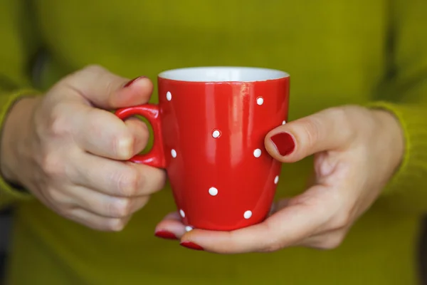 Woman hands holding a cozy red mug — Stock Photo, Image