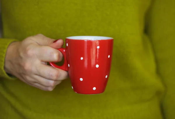 Mãos de mulher segurando uma caneca vermelha acolhedora — Fotografia de Stock