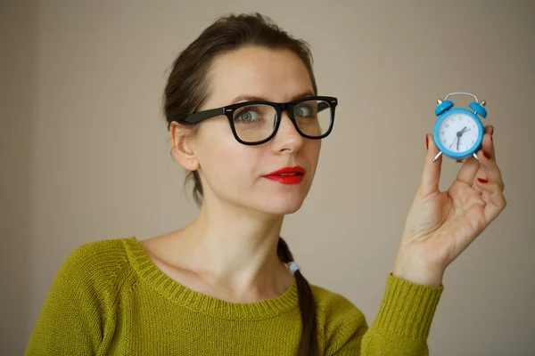 Kleiner blauer Wecker in den Händen einer emotionalen jungen Frau — Stockfoto