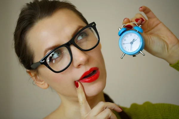 Kleiner blauer Wecker in den Händen einer emotionalen jungen Frau — Stockfoto