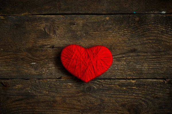 Forma de corazón rojo hecho de lana sobre fondo de madera viejo y maltrecho —  Fotos de Stock