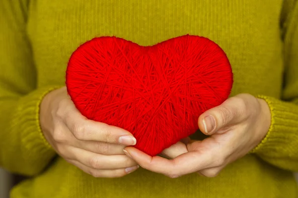 Primer plano en el corazón rojo de lana en la mano de la mujer — Foto de Stock