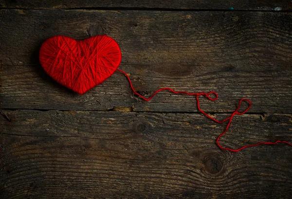 Red heart shape made from wool on old shabby wooden background — Stock Photo, Image