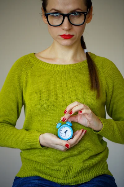 Kleiner blauer Wecker in den Händen einer emotionalen jungen Frau — Stockfoto