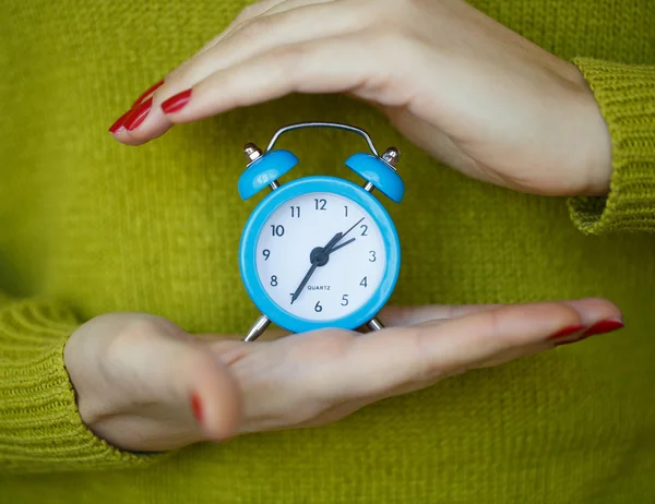 Pequeno despertador azul nas mãos da mulher — Fotografia de Stock