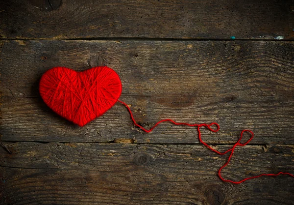 Red heart shape made from wool on old shabby wooden background — Stock Photo, Image