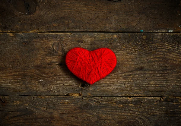 Forma de corazón rojo hecho de lana sobre fondo de madera viejo y maltrecho —  Fotos de Stock