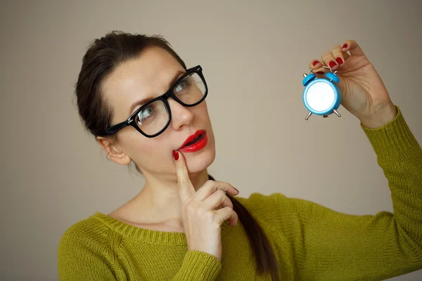 Little blue alarm clock in the hands of an emotional young woman — Stock Photo, Image