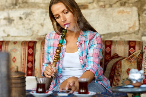 Frau raucht Wasserpfeife und benutzt Smartphone in einem Café in Istanbu — Stockfoto