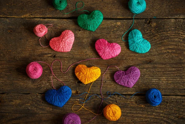 Multicolored Hearts with a balls of thread on old shabby wooden — Stock Photo, Image