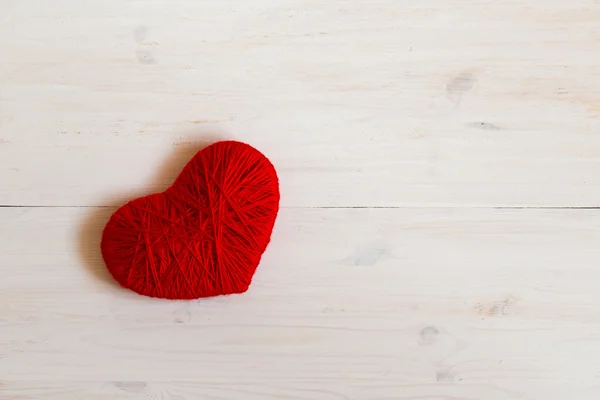 Forma de coração vermelho feito de lã no fundo de madeira branco — Fotografia de Stock