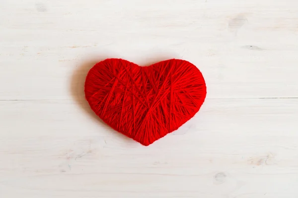 Forma de coração vermelho feito de lã no fundo de madeira branco — Fotografia de Stock