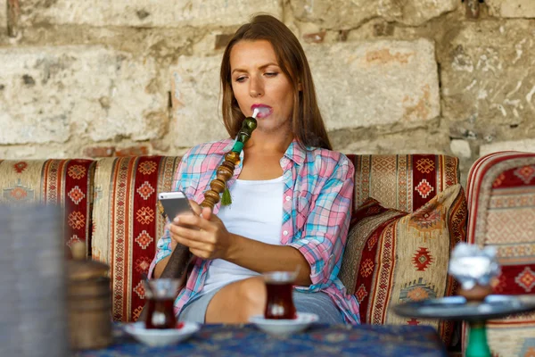 Mulher fumando um narguilé e usando smartphone em um café em Istanbu — Fotografia de Stock