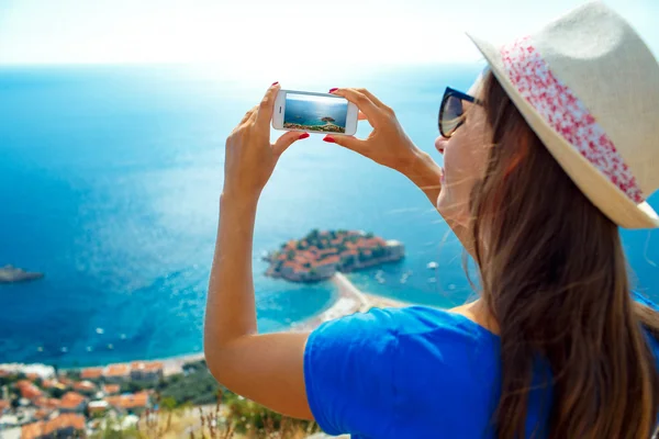 Menina no chapéu fazendo fotos pelo smartphone perto da ilha — Fotografia de Stock