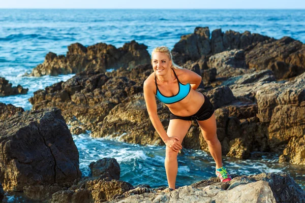Αθλητής γυναίκα να στέκεται μετά την άσκηση άθλημα στα βράχια από ου — Φωτογραφία Αρχείου