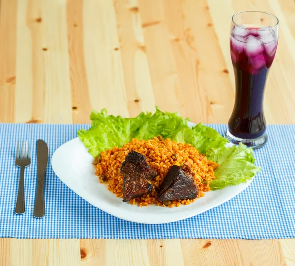 Schotel van Rosbief met rijst en salade bladeren en een glas jui — Stockfoto