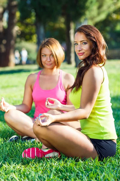 Dos chicas jóvenes relajándose al aire libre, practicando yoga —  Fotos de Stock