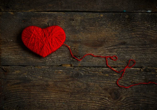 Forma de corazón rojo hecho de lana sobre fondo de madera viejo y maltrecho —  Fotos de Stock