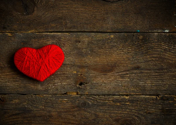 Forma de corazón rojo hecho de lana sobre fondo de madera viejo y maltrecho —  Fotos de Stock