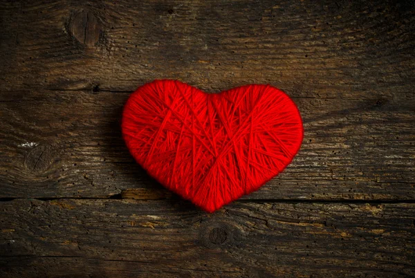 Красная форма сердца, сделанная из шерсти на старом потрепанном деревянном фоне — стоковое фото