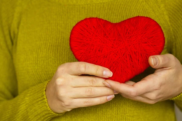 Primer plano en el corazón rojo de lana en la mano de la mujer — Foto de Stock