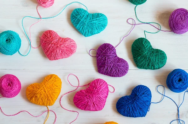 Multicolored Hearts with a balls of thread on white wooden backg — Stock Photo, Image