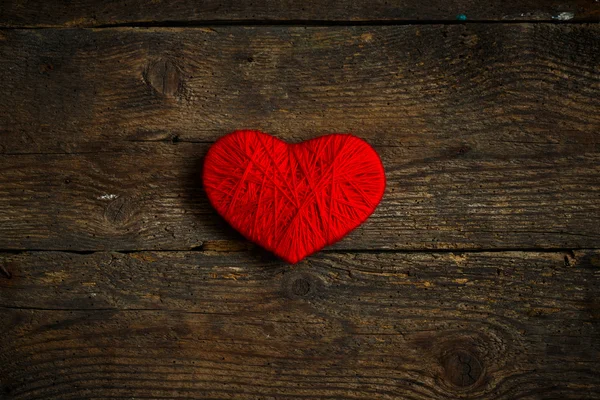 Rött hjärta form gjorda av ull på gammal shabby trä bakgrund — Stockfoto
