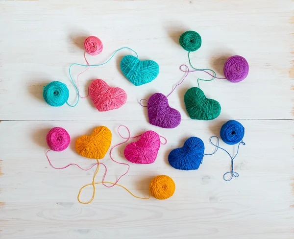 Veelkleurige hart met een ballen van draad op witte houten backg — Stockfoto