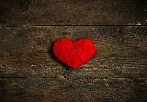 Forma di cuore rosso fatto di lana su vecchio sfondo di legno squallido — Foto Stock