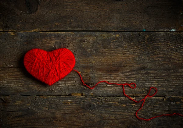 Красная форма сердца, сделанная из шерсти на старом потрепанном деревянном фоне — стоковое фото