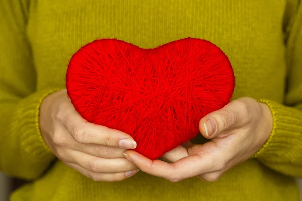 Close-up op rood hart gemaakt van wol in hand van vrouw — Stockfoto