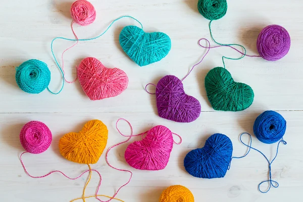 Veelkleurige hart met een ballen van draad op witte houten backg — Stockfoto