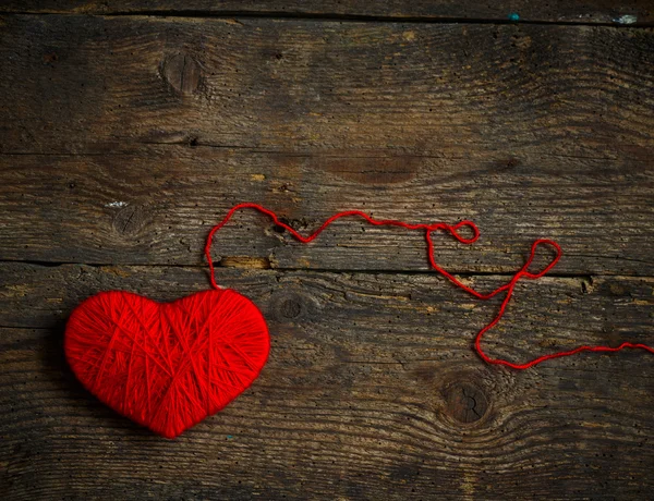 Red heart shape made from wool on old shabby wooden background — Stock Photo, Image