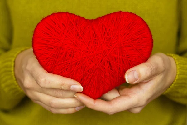 Fechar no coração vermelho feito de lã na mão da mulher — Fotografia de Stock