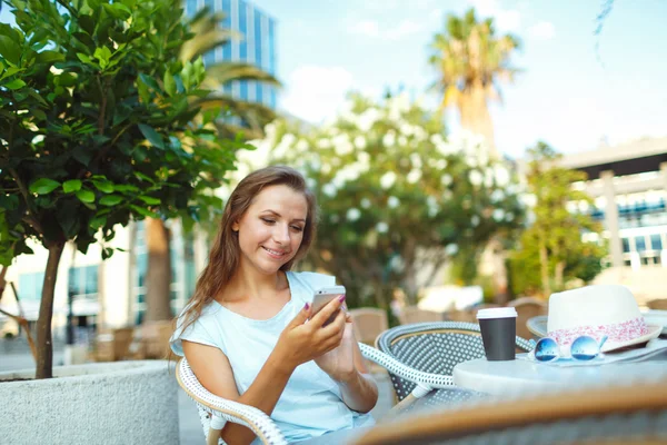 Fiatal, csinos nő lazíthatnak a szabadtéri kávézó és smartp segítségével — Stock Fotó