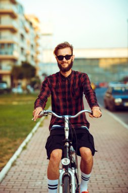 Genç adam bir şehir sokak Bisiklete binmek güneş gözlüğü