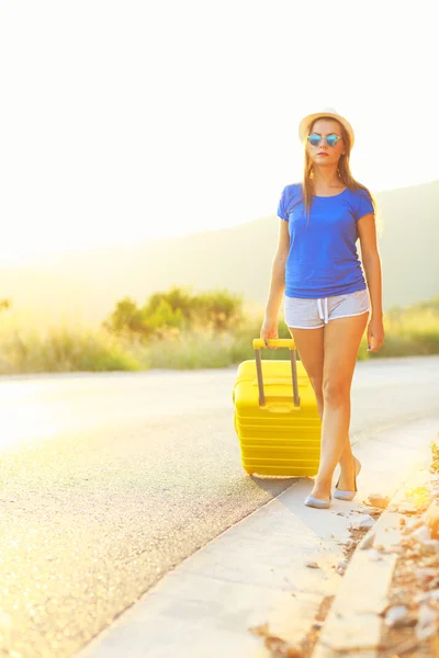 道路高温超伝導の黄色のスーツケースを持つ若い女性を旅行します。 — ストック写真