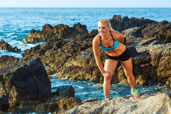 Αθλητής γυναίκα να στέκεται μετά την άσκηση άθλημα στα βράχια από ου — Φωτογραφία Αρχείου