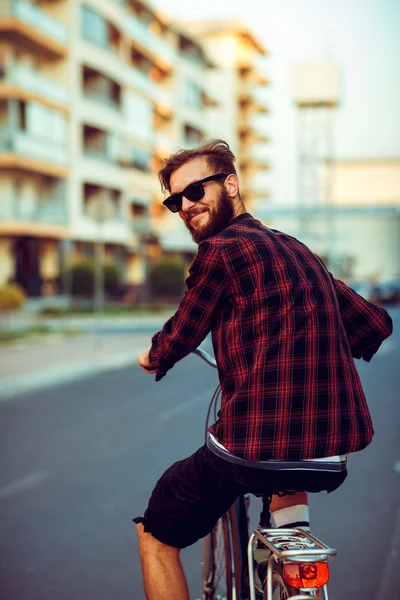 Giovane uomo in occhiali da sole in bicicletta sulla strada della città — Foto Stock
