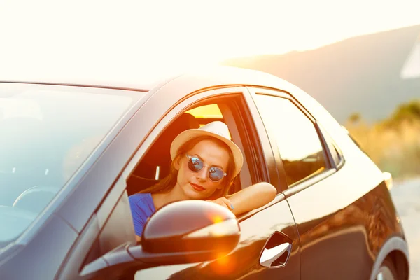 Donna sorridente alla guida di una macchina al tramonto — Foto Stock