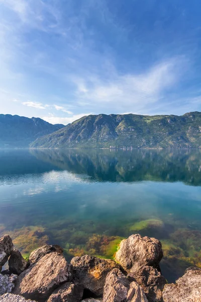 Spiaggia di pietra con mare e montagna — Foto Stock