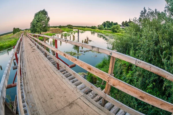 Bridge over a swampy river in sunset time — Stock Photo, Image