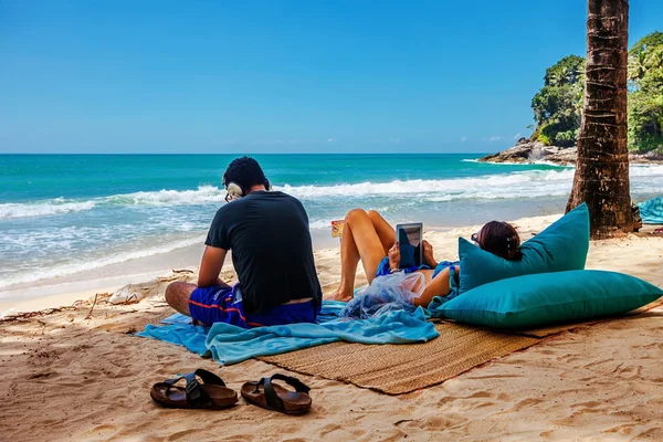 Člověk poslouchá hudbu a žena používá tablet na tropica — Stock fotografie